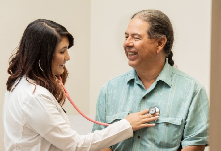 A medical provider listening to a patient's heartbeat through a stethoscope